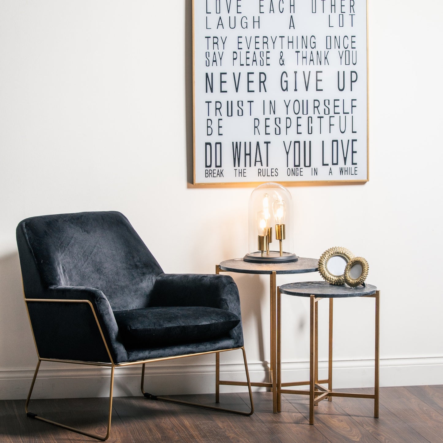 Modern interior with a dark gray armchair, side tables, and a motivational poster on the wall.