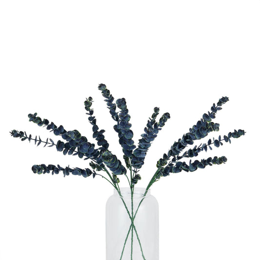 Bouquet of dark green artificial eucalyptus branches in a clear glass vase on a white background