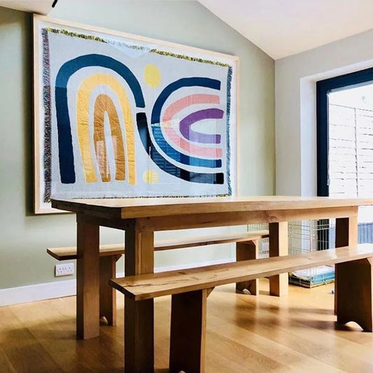 Wooden dining table with benches and abstract wall art in a room.
