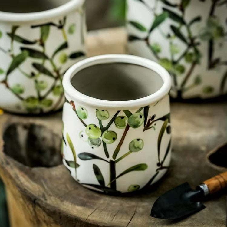 Ceramic pot with green leaf design on a wooden surface