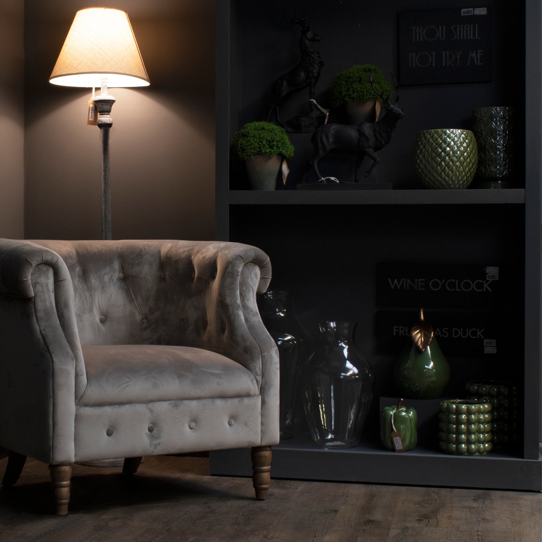 Gray armchair in a dimly lit room with decorative shelves and lighting.