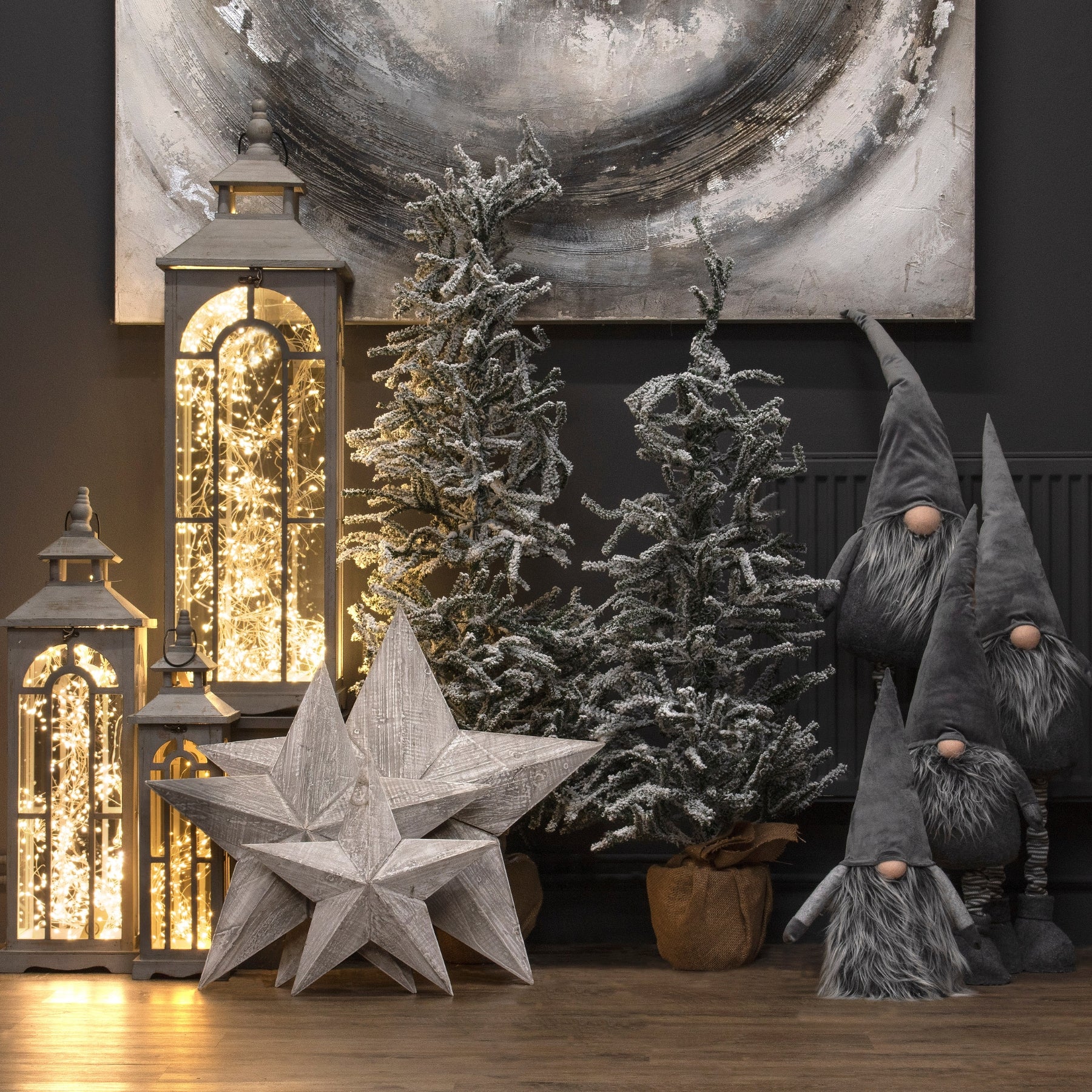 Decorative setup with Christmas trees, lanterns, and gnomes against a dark wall.