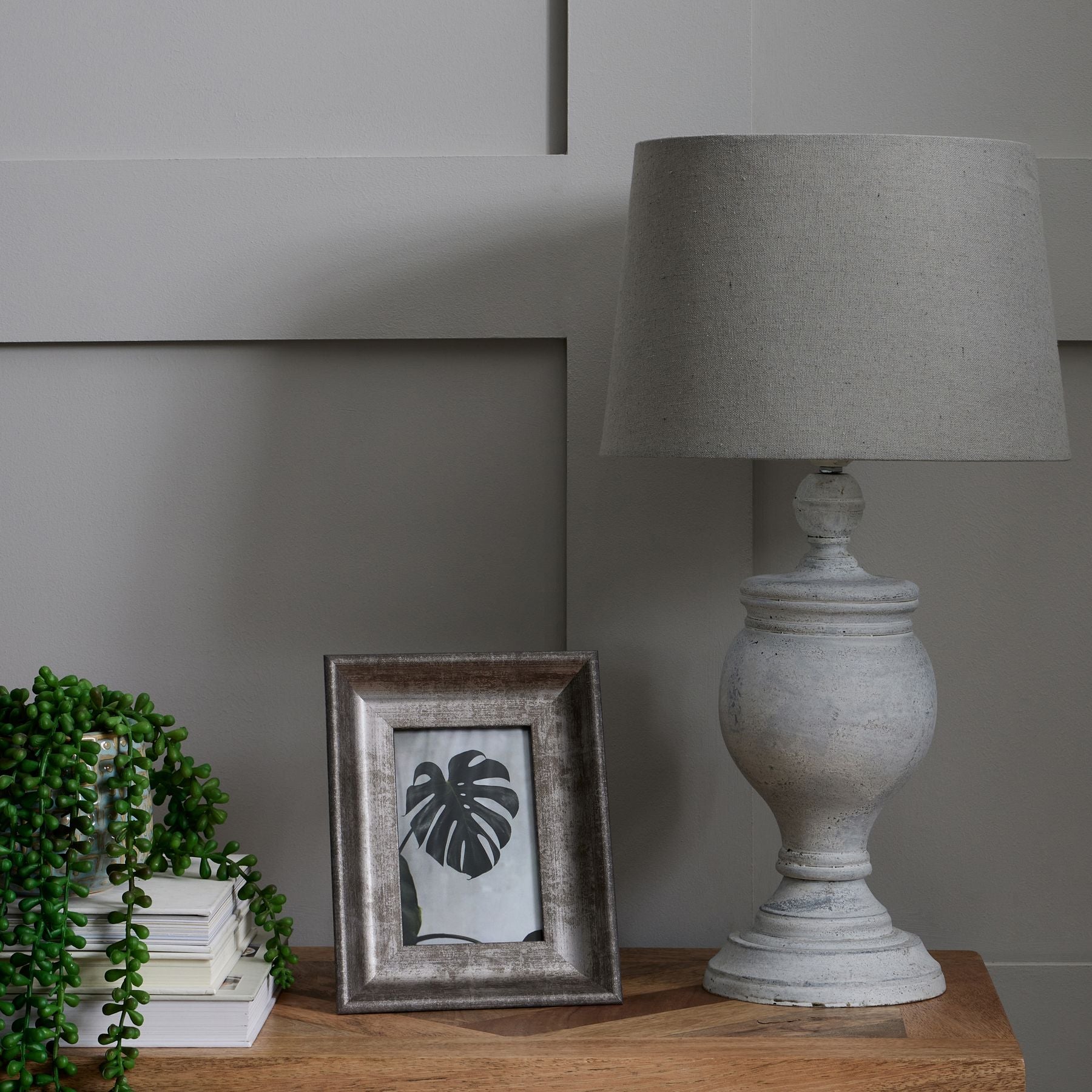 Decorative lamp and framed picture on a wooden surface with a neutral background