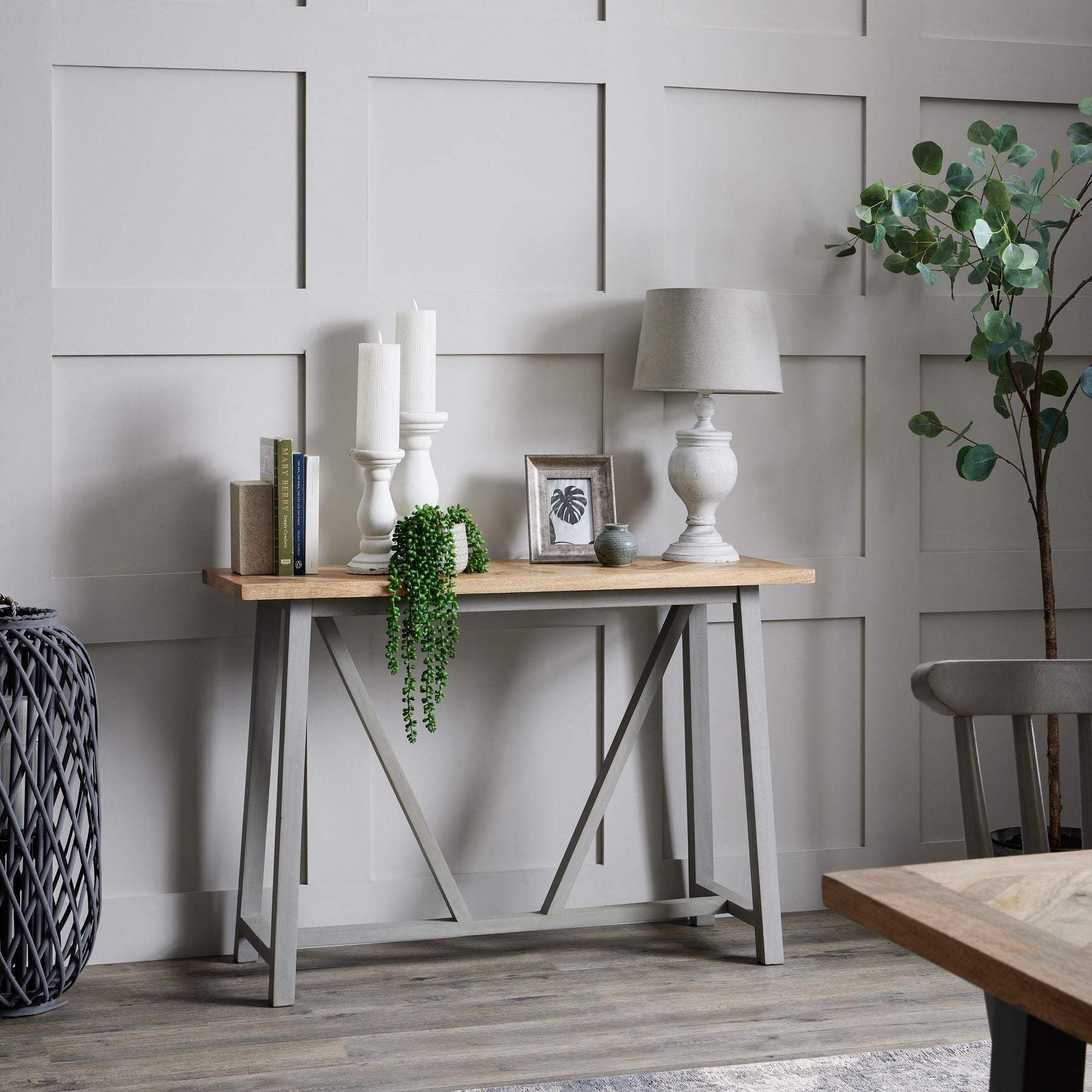 Wooden console table with decorative items against a paneled wall.