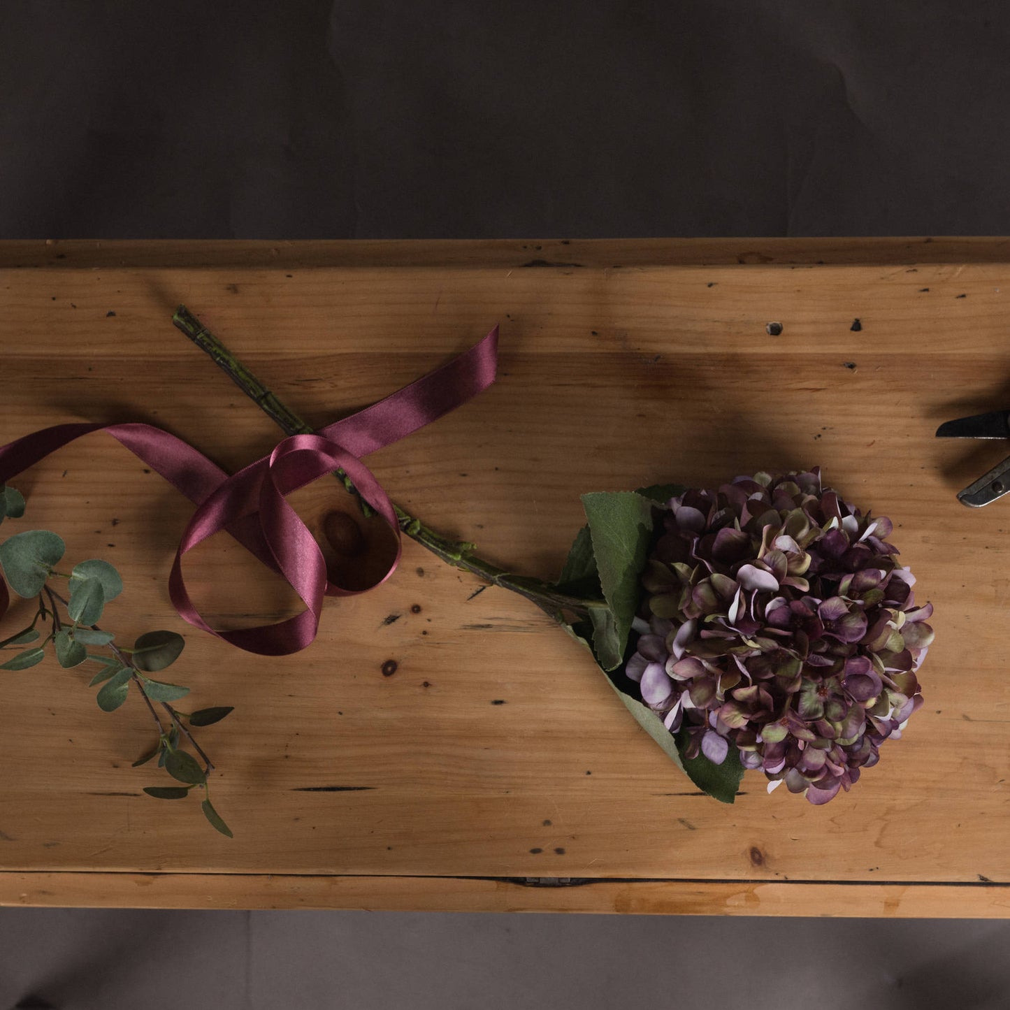 Purple flowers and green leaves on a wooden surface