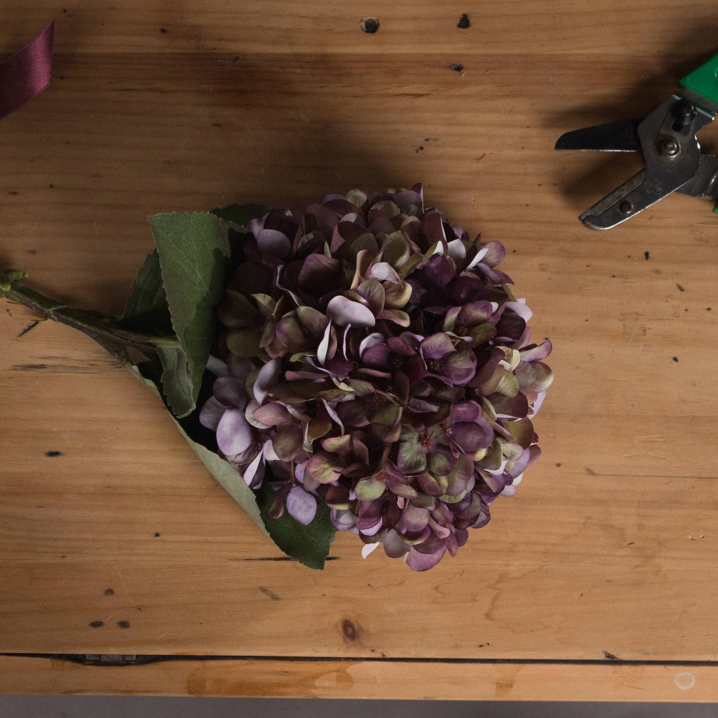 Purple flower bouquet on a wooden surface with a pair of scissors.