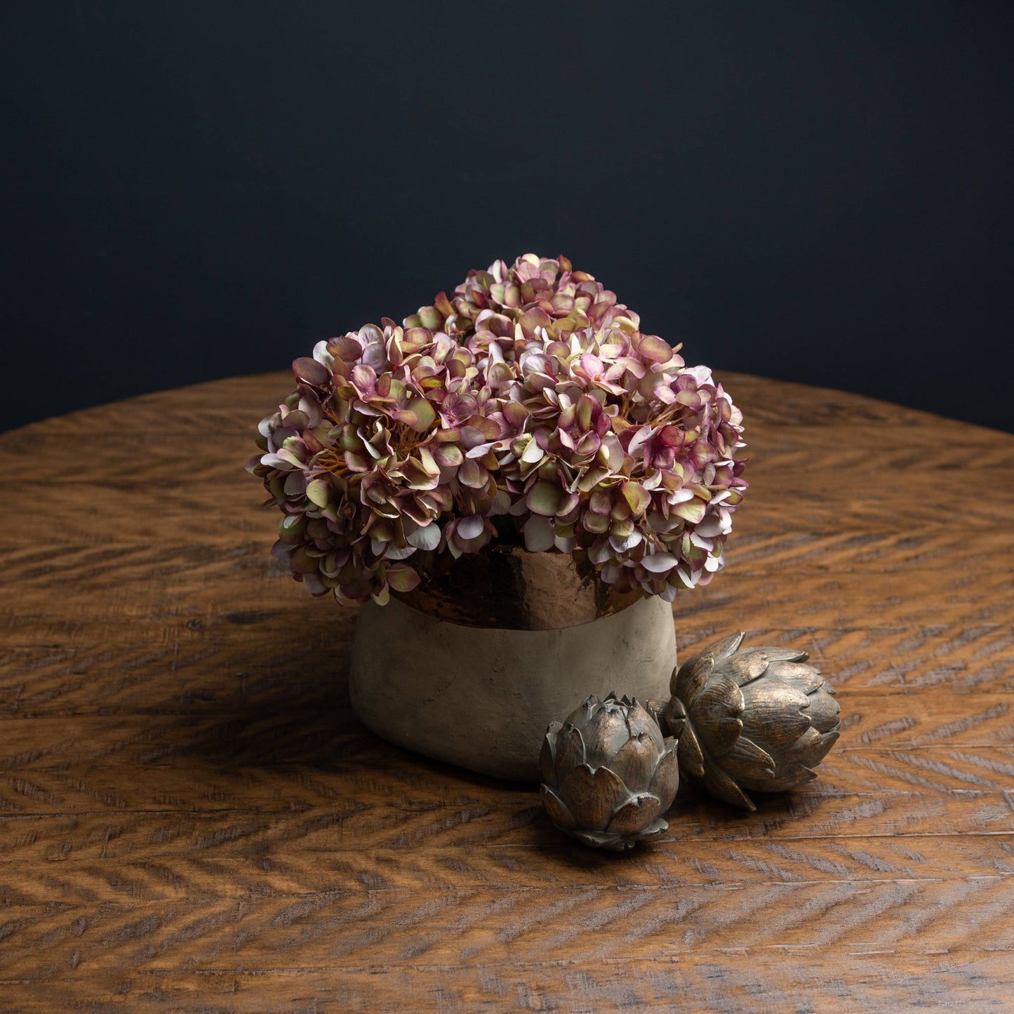 Decorative arrangement of flowers and artichokes on a wooden surface with a dark background