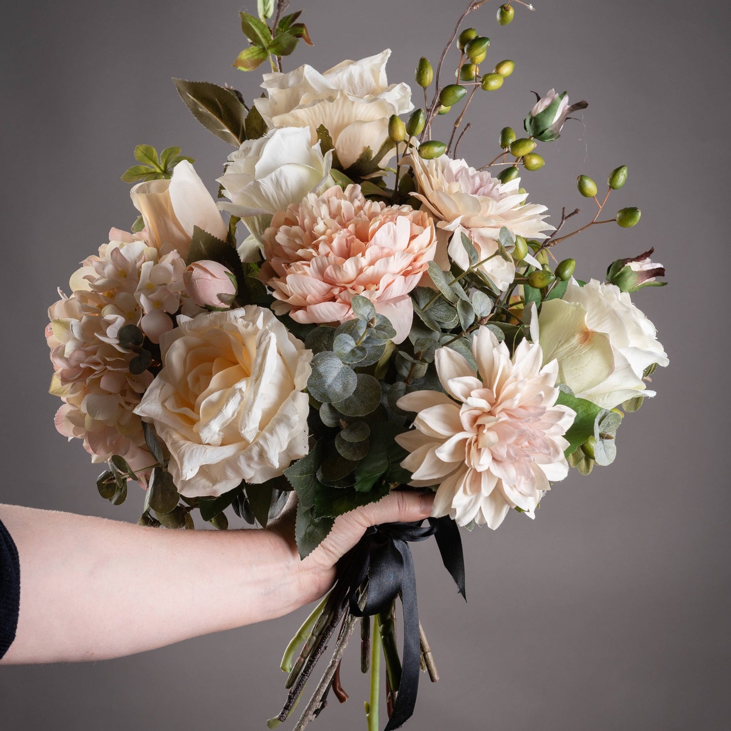 Bouquet of flowers held by a person against a gray background