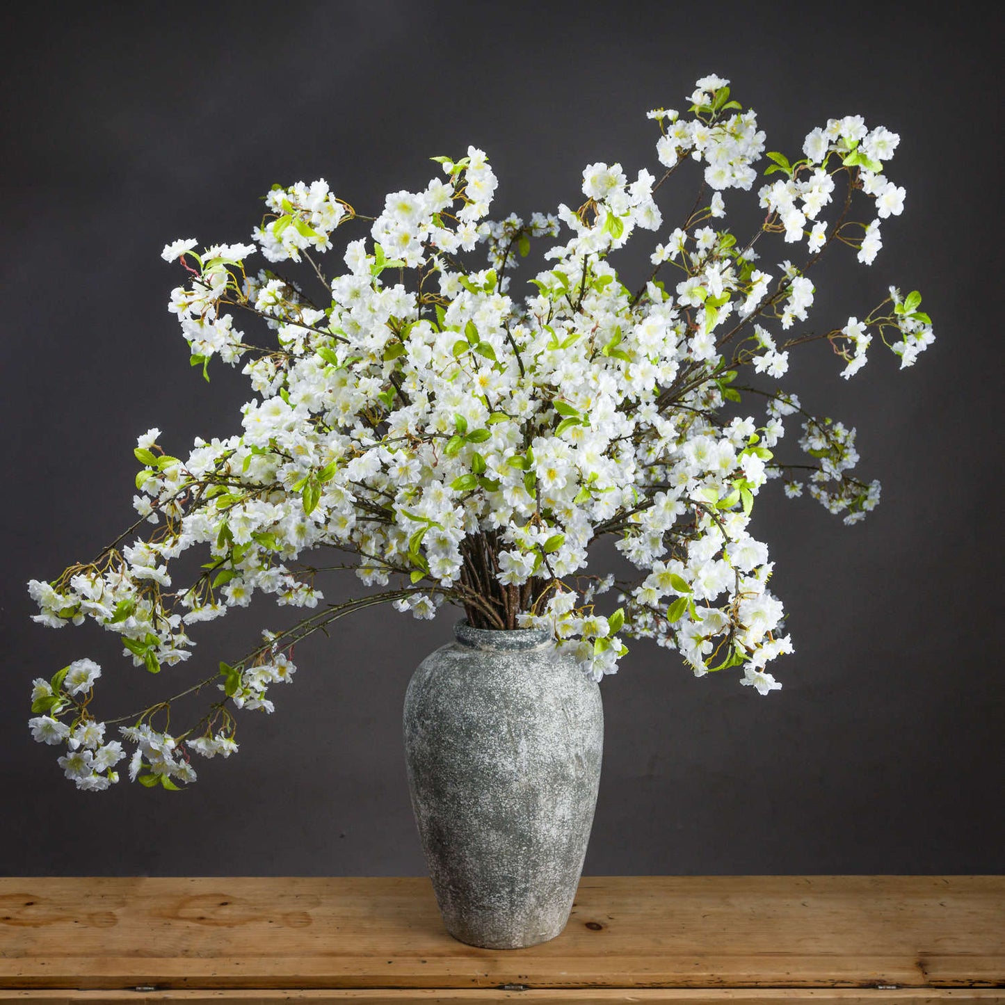 Vase with white flowers on a wooden surface against a dark background