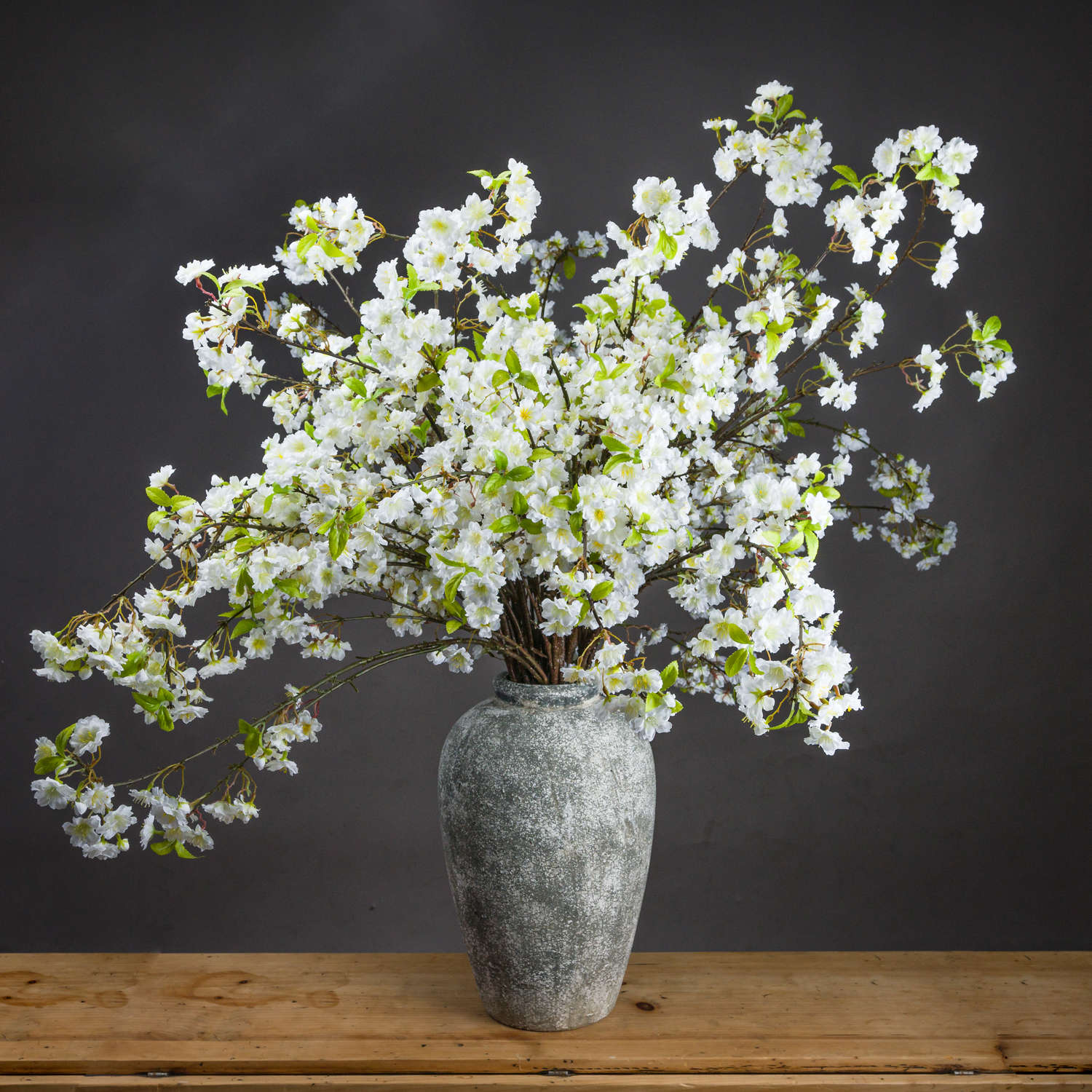 Vase with white flowers on a wooden surface against a dark background