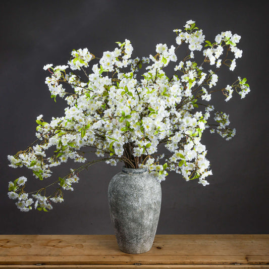 Vase with white flowers on a wooden surface against a dark background