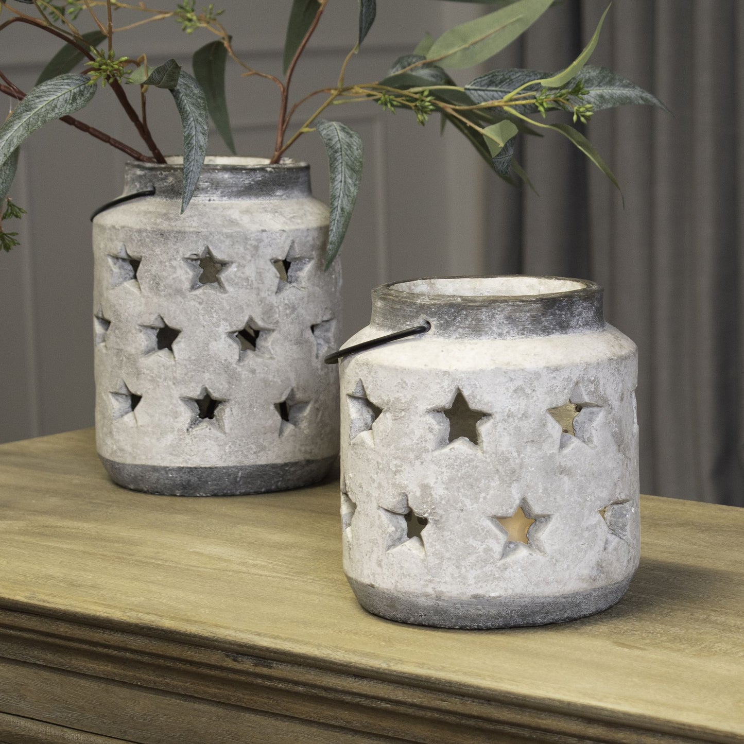 Two decorative lanterns with star cutouts on a wooden surface.