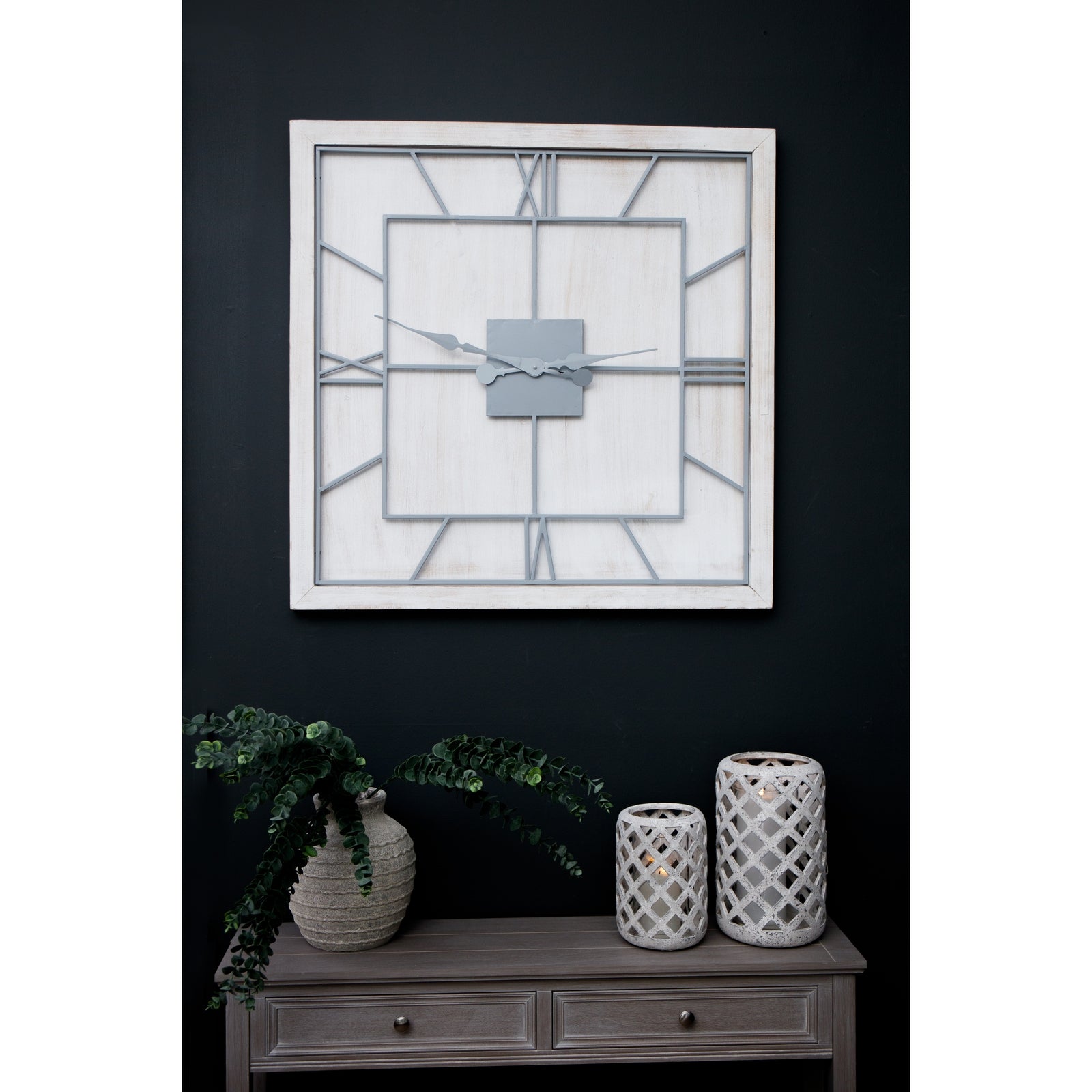 Decorative wall clock with geometric design on a dark wall above a wooden console table.