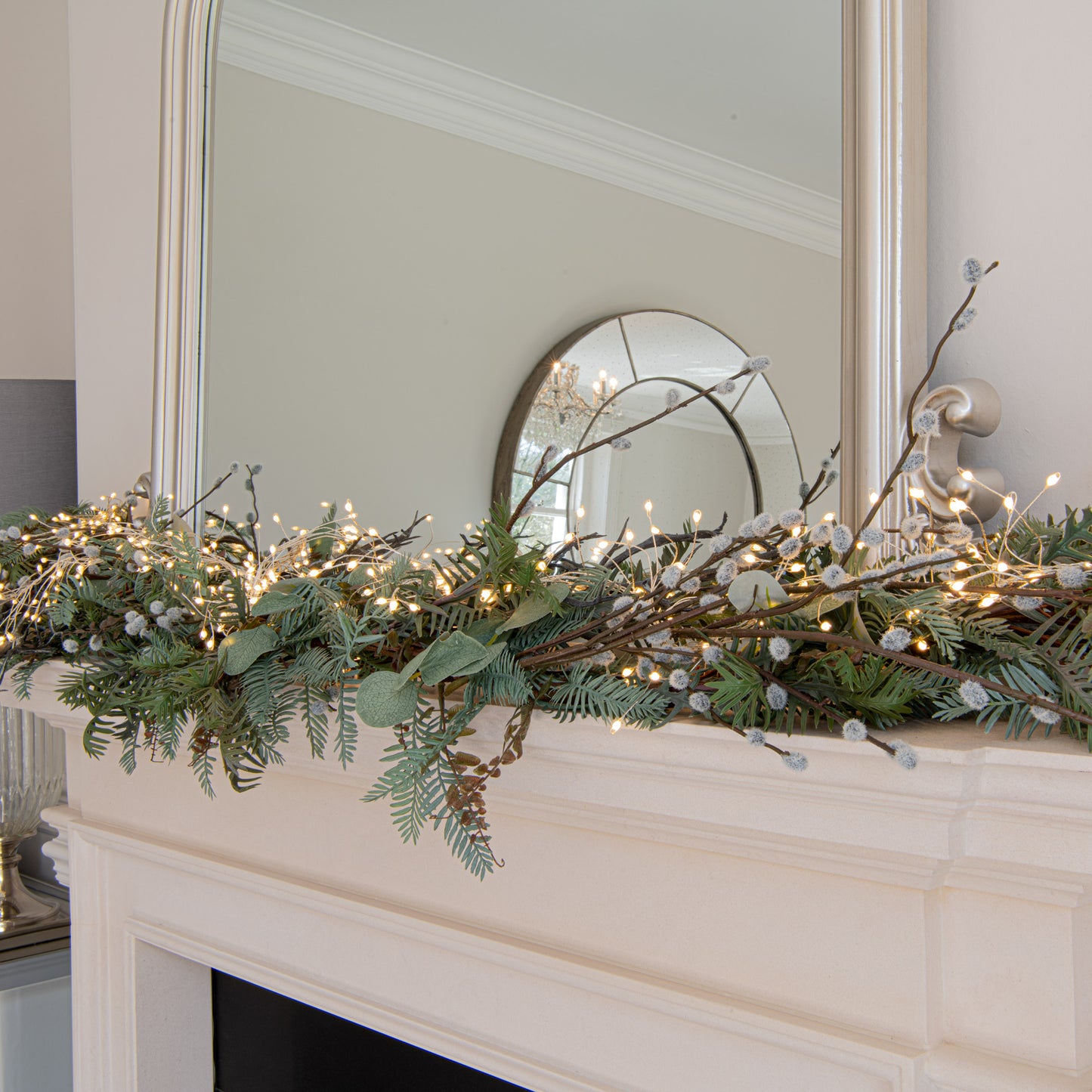 Decorative greenery with lights on a fireplace mantel in a home setting.