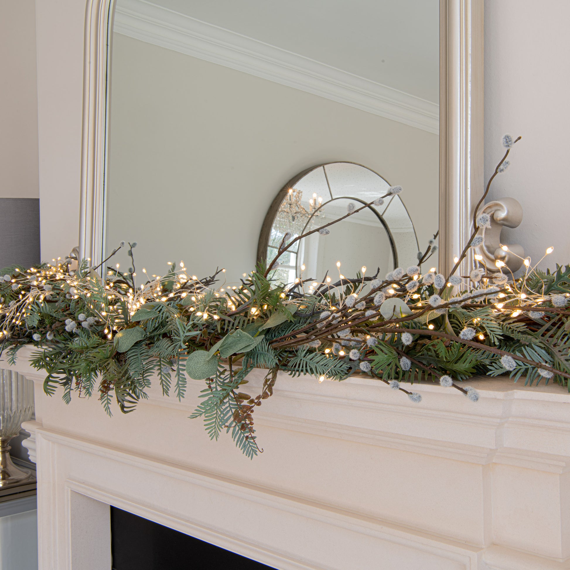Decorative greenery with lights on a fireplace mantel in a home setting.