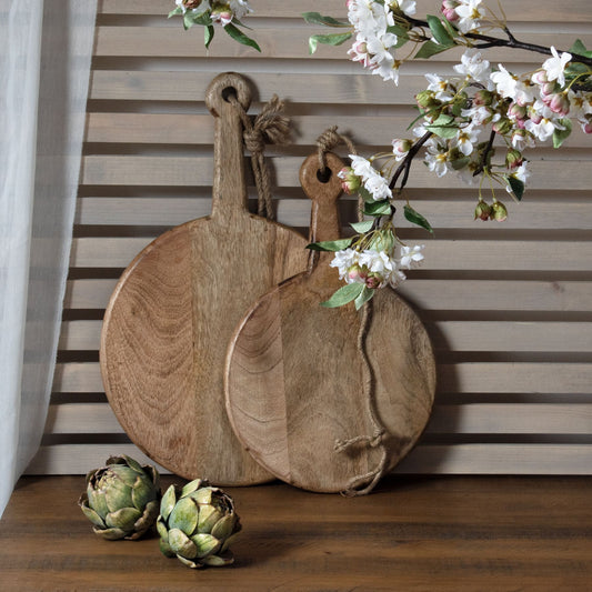 Three wooden cutting boards with a decorative flower arrangement on a wooden surface.