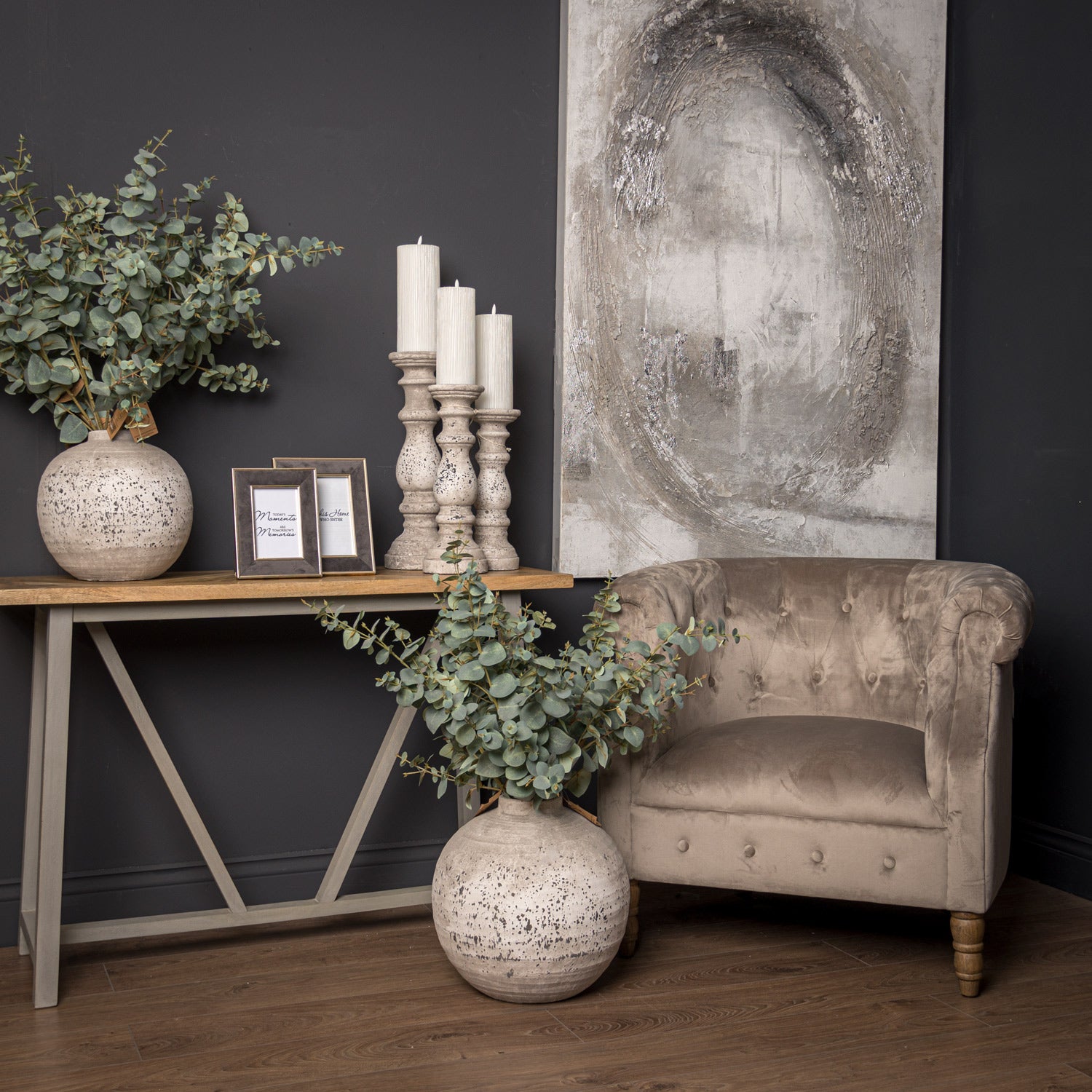 Living room with a beige armchair, decorative table, and wall art.