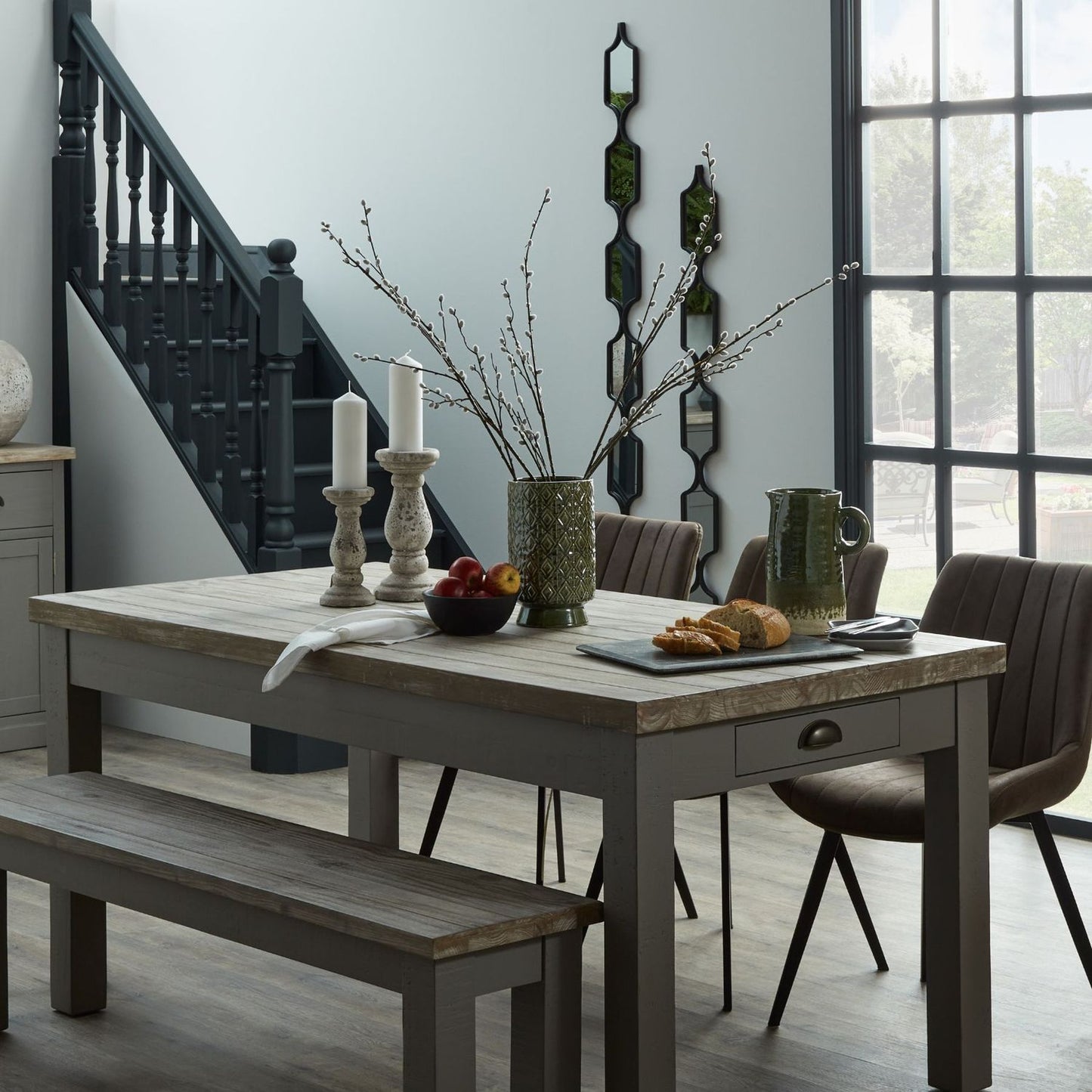 Dining room with a wooden table set for a meal, featuring chairs and a bench.