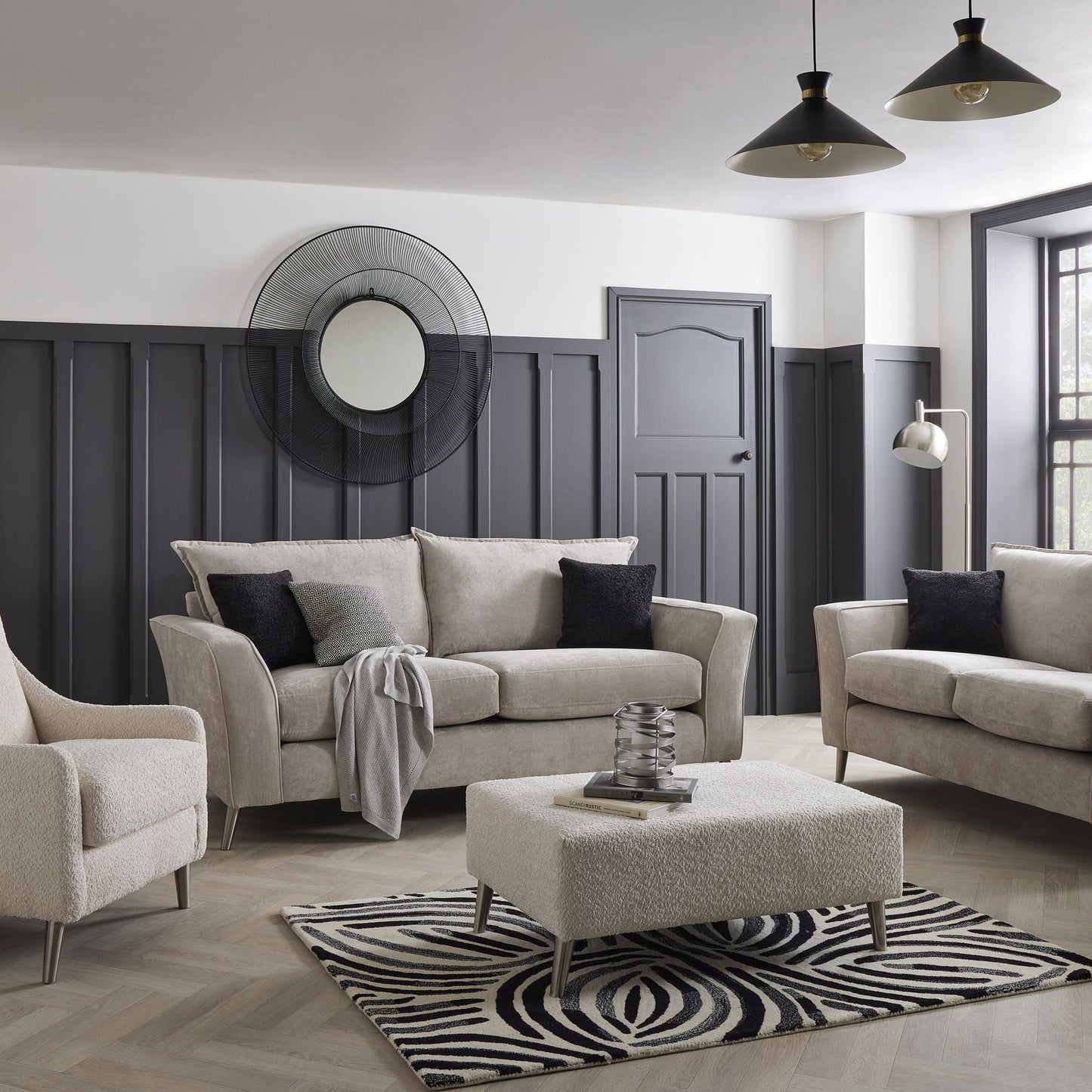 Modern living room with gray sofas, armchair, and ottoman on a zebra print rug.