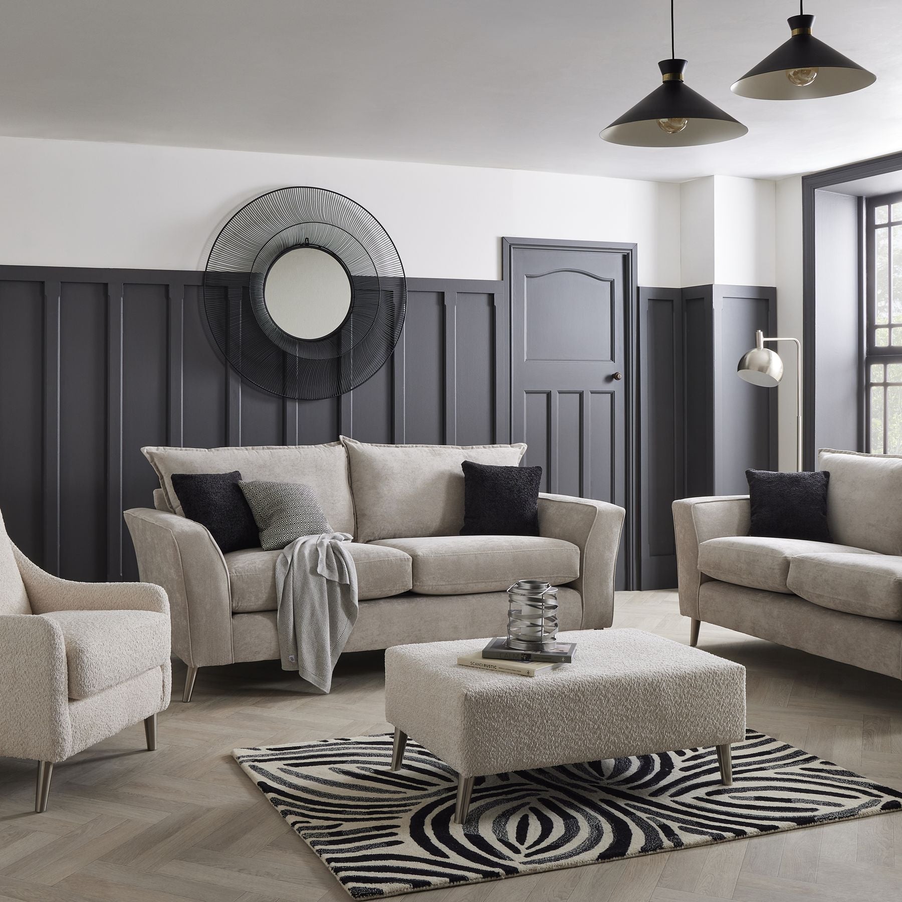 Modern living room with gray sofas, armchair, and ottoman on a zebra print rug.