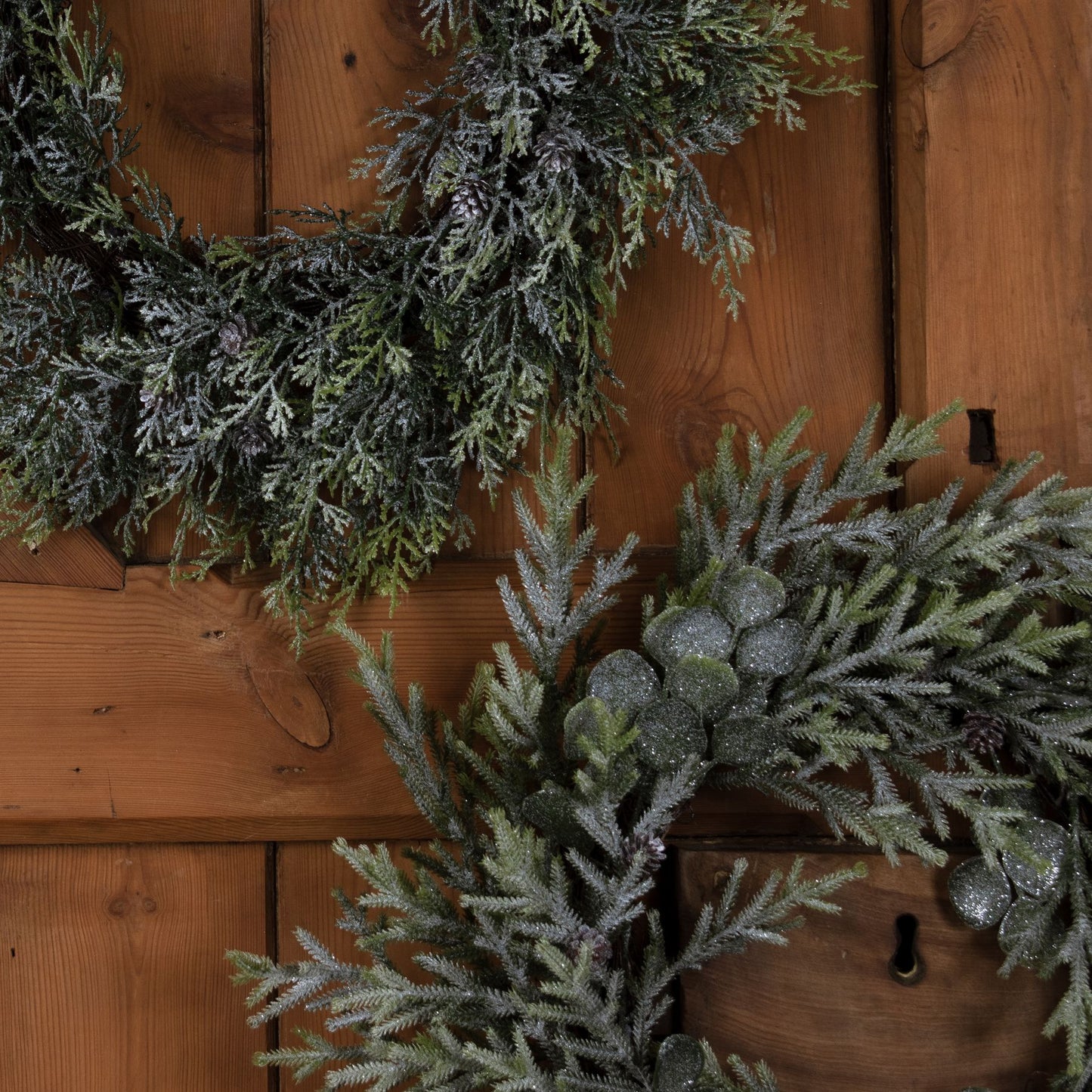 Decorative evergreen wreaths against a wooden wall