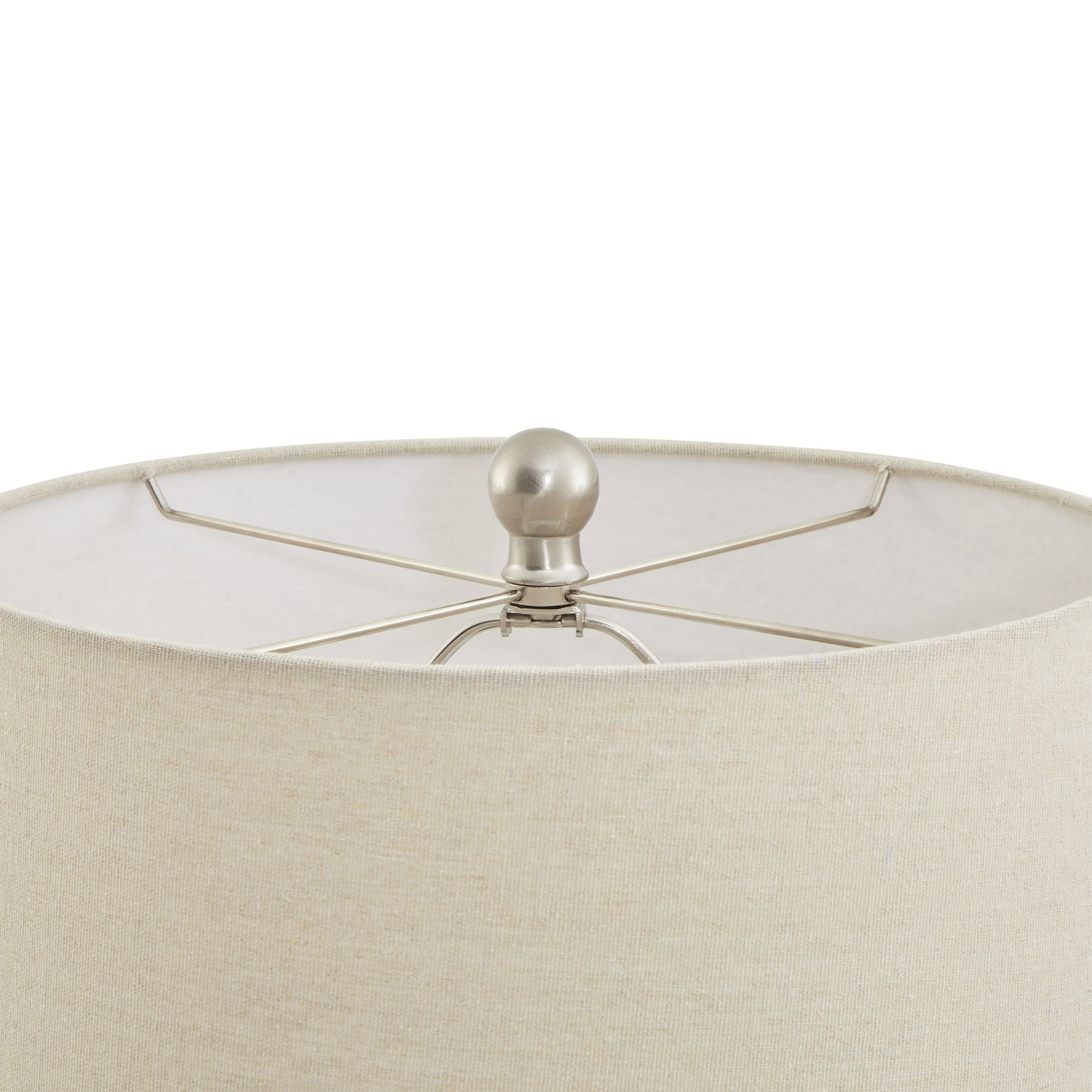 Close-up of a beige lampshade with a metallic finial on a white background