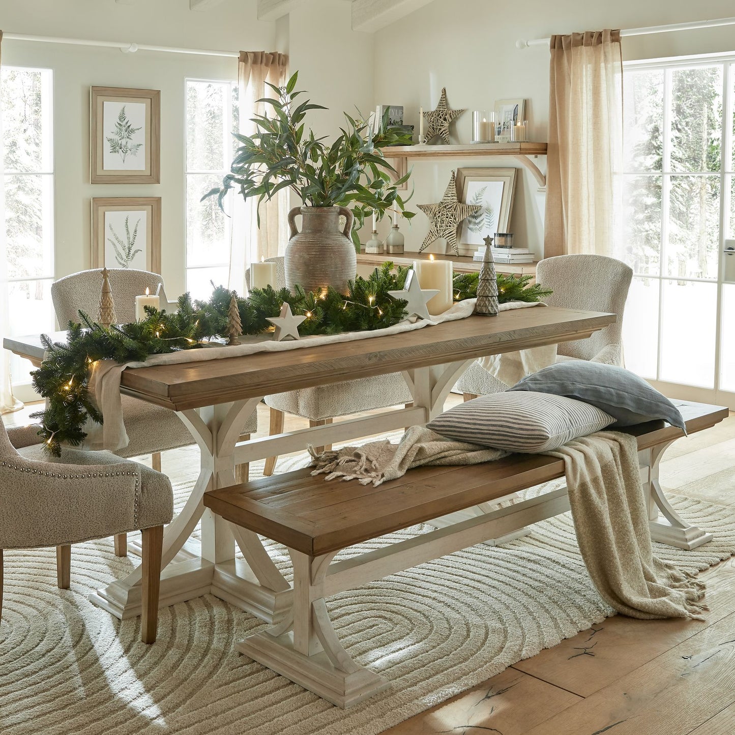 Dining room with a long wooden table set for a meal, decorated with greenery and candles.