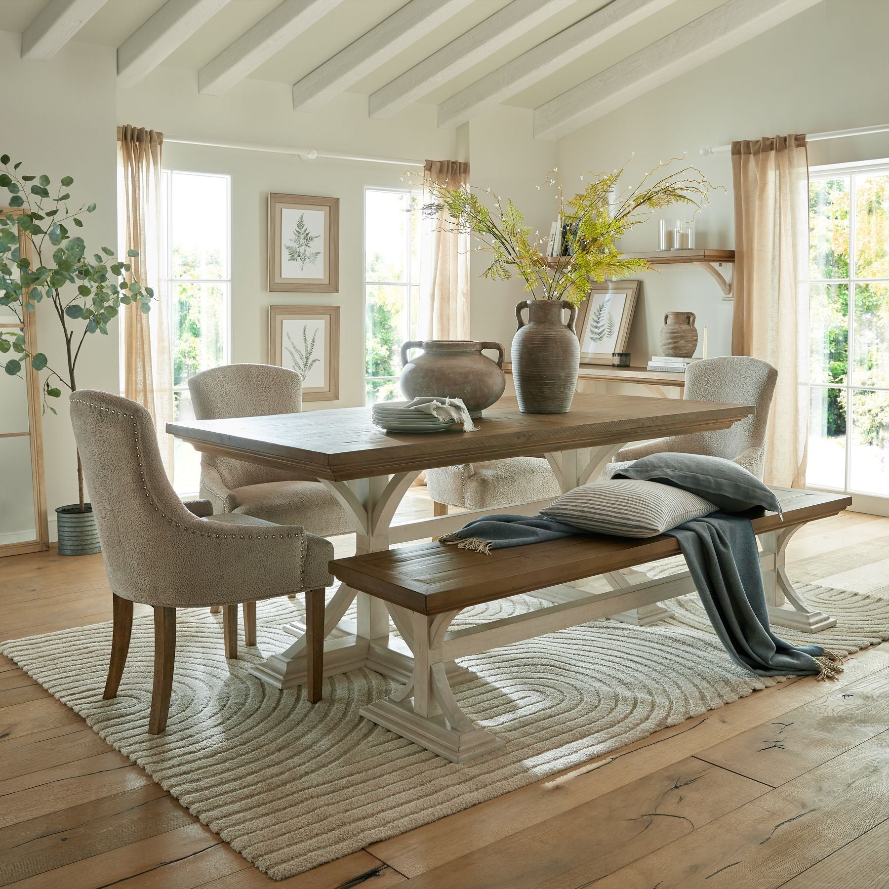 Dining room with wooden table, chairs, and bench on a patterned rug.