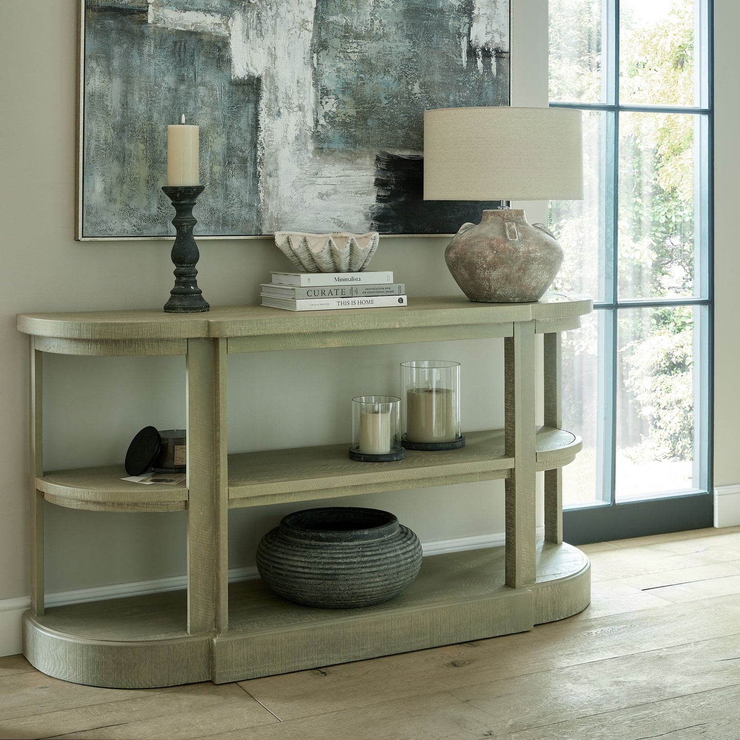 Decorative console table with various items in a room with a large window.
