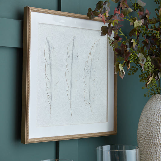 Framed artwork on a teal wall with a vase and plant
