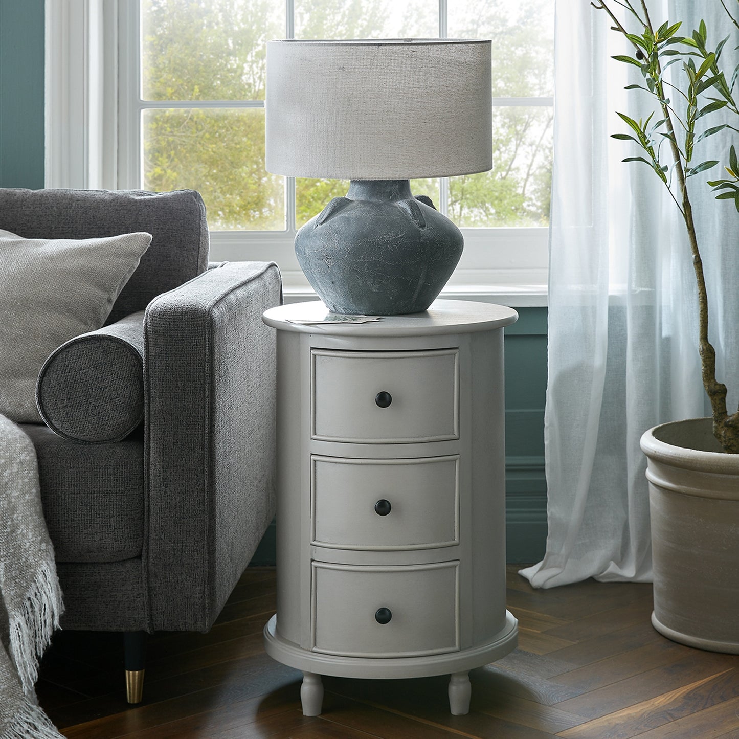 Gray side table with lamp next to a gray sofa in a living room.