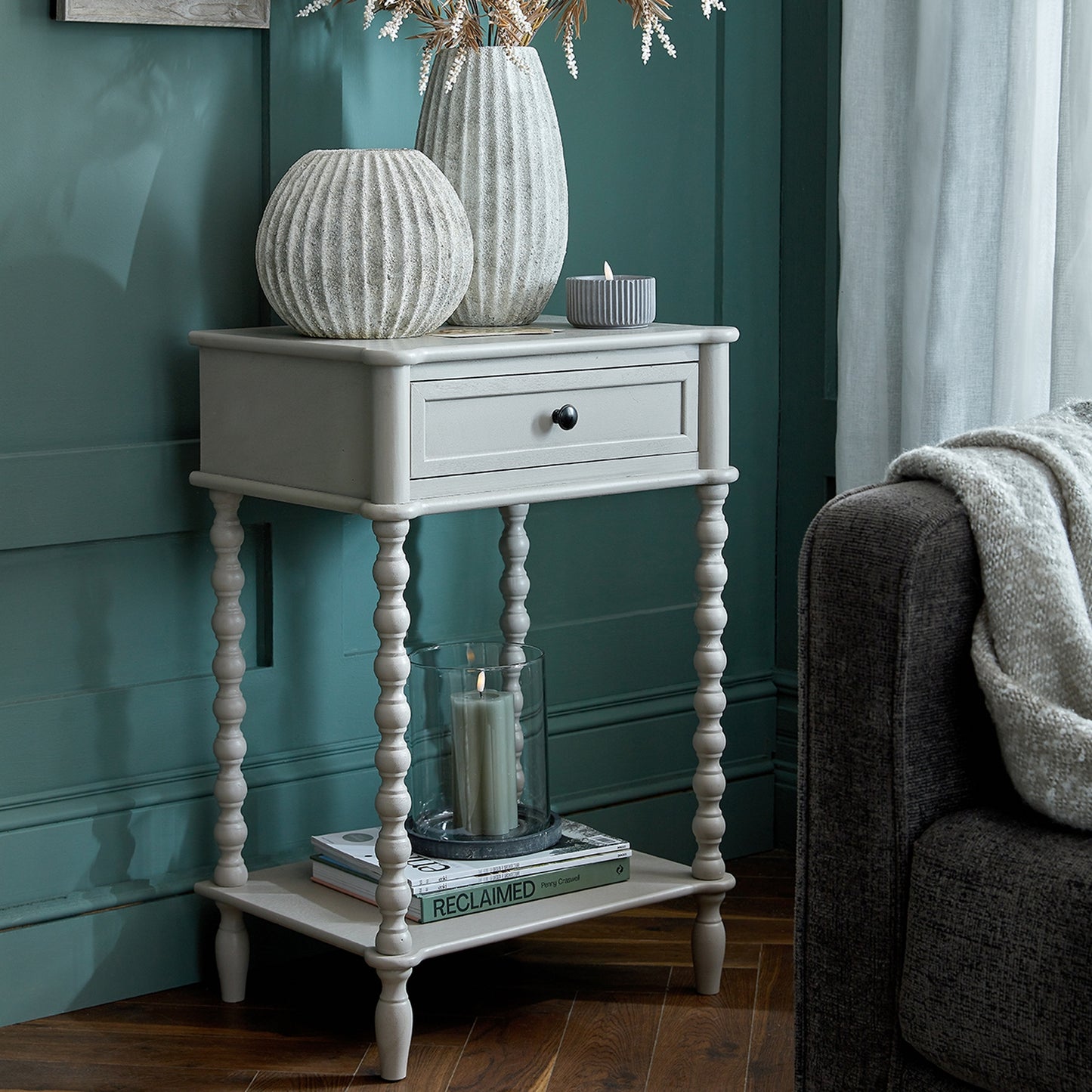 White side table with decorative items against a teal wall