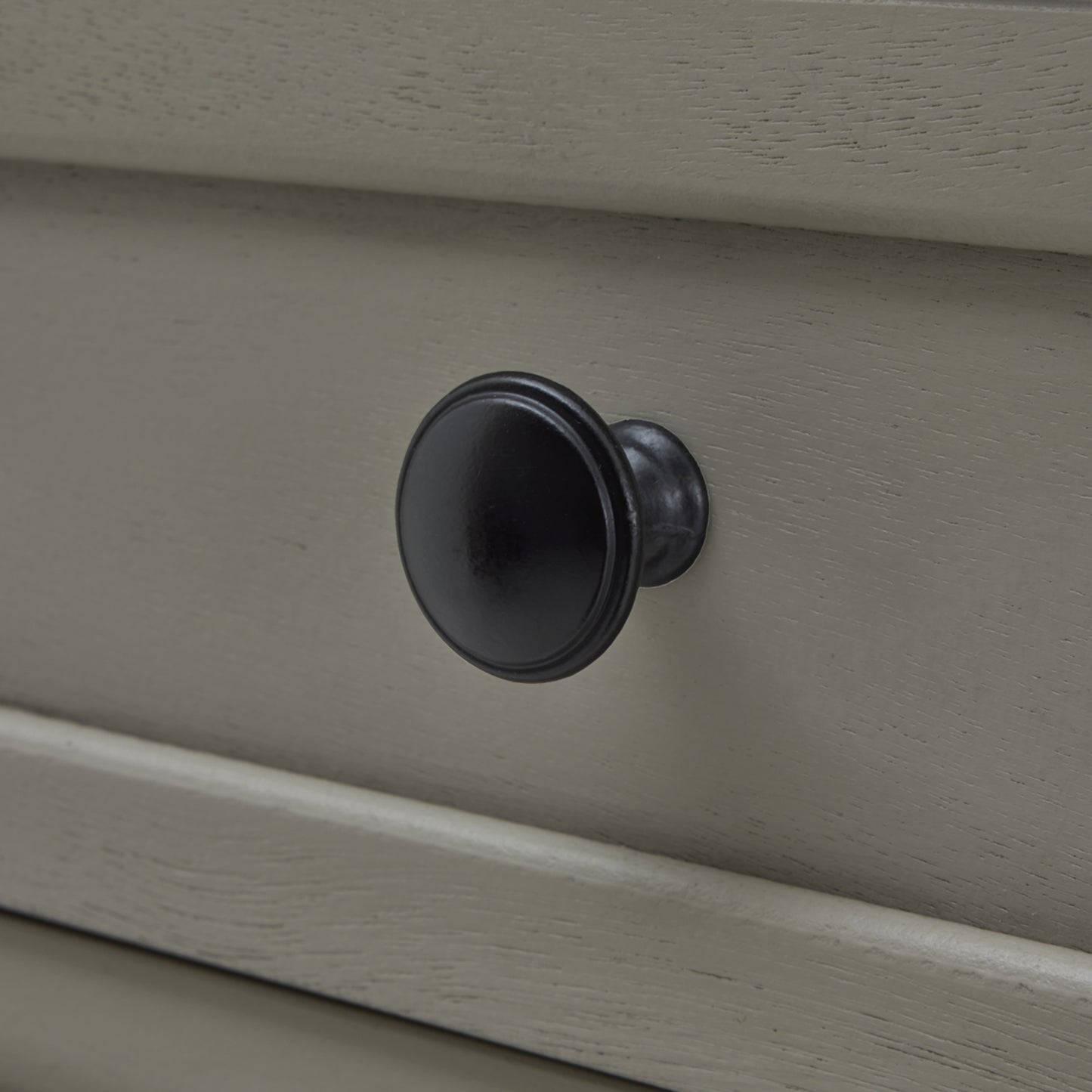 Close-up of a black cabinet knob on a beige drawer