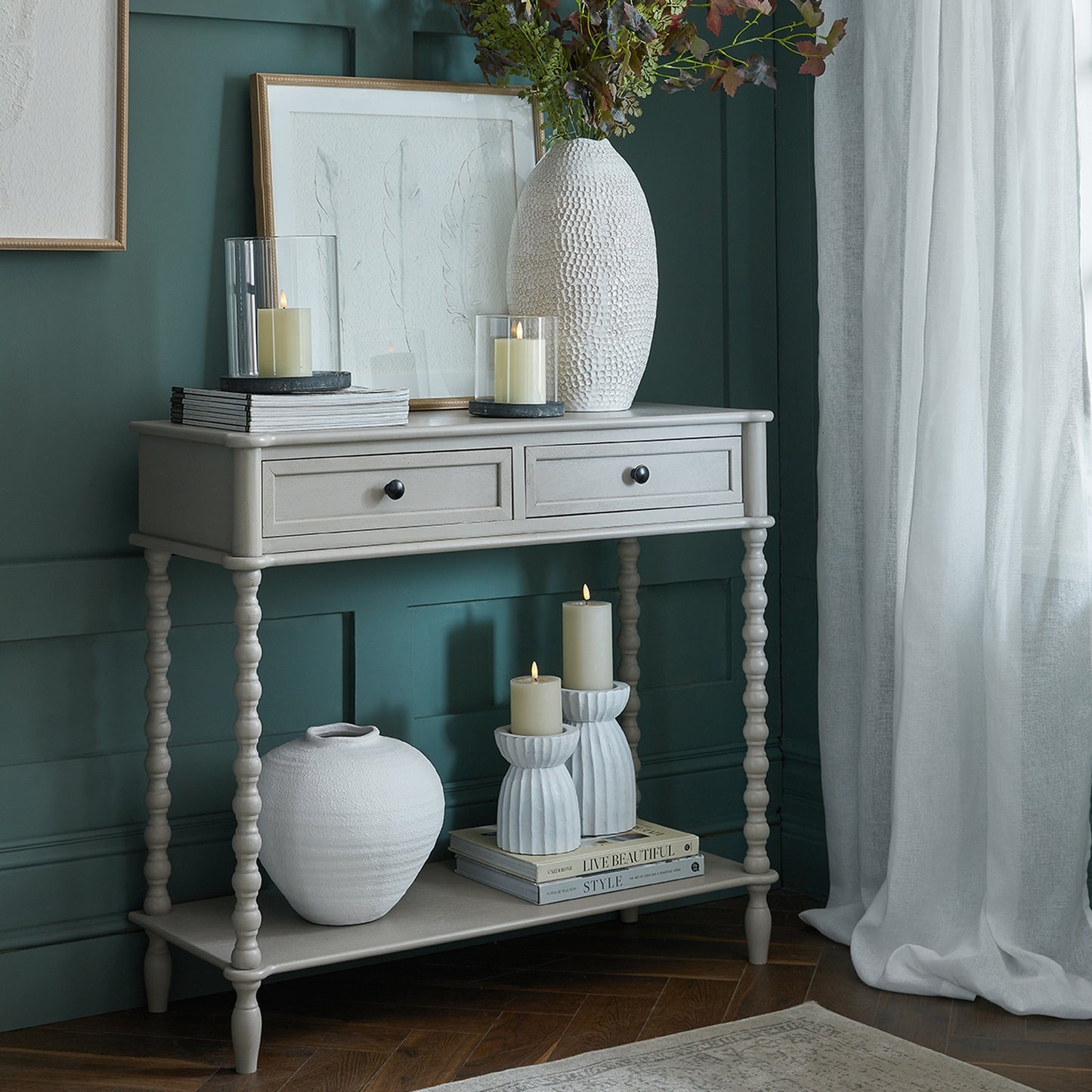 Console table with decorative items against a teal wall