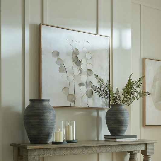 Decorative setting with vases, candles, and framed artwork on a wall.