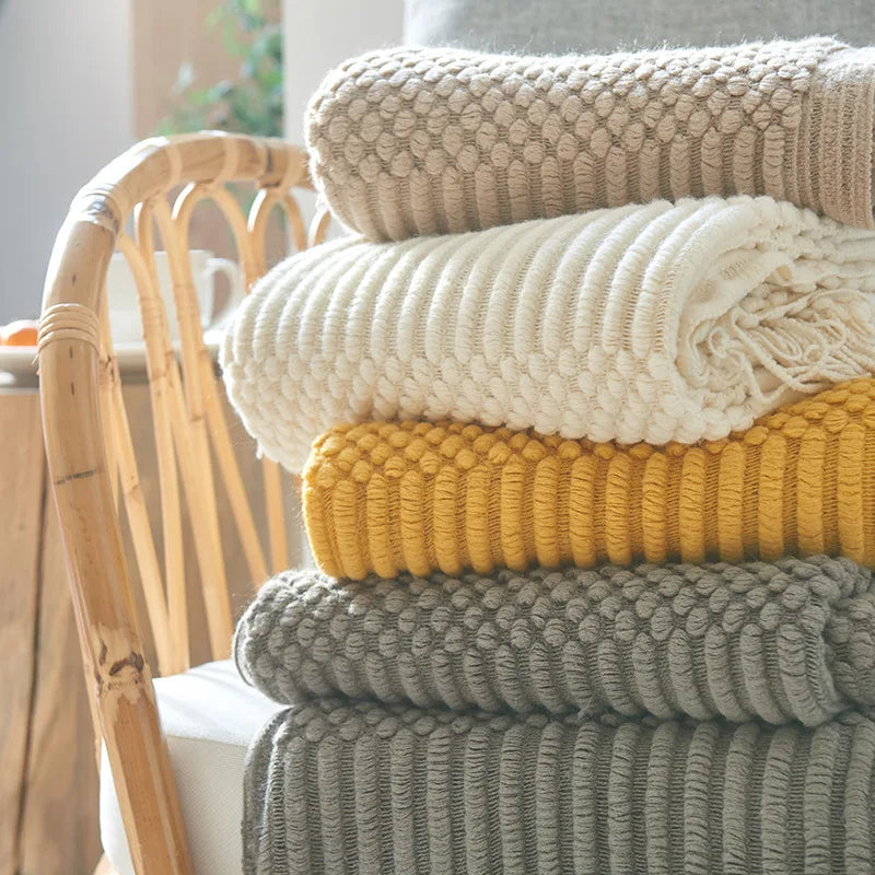Stack of colorful knitted blankets on a chair