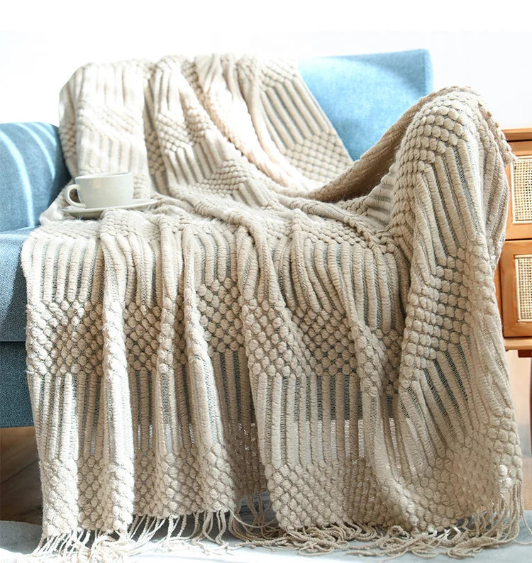 Textured beige blanket draped over a chair with a cup on a blue cushion.