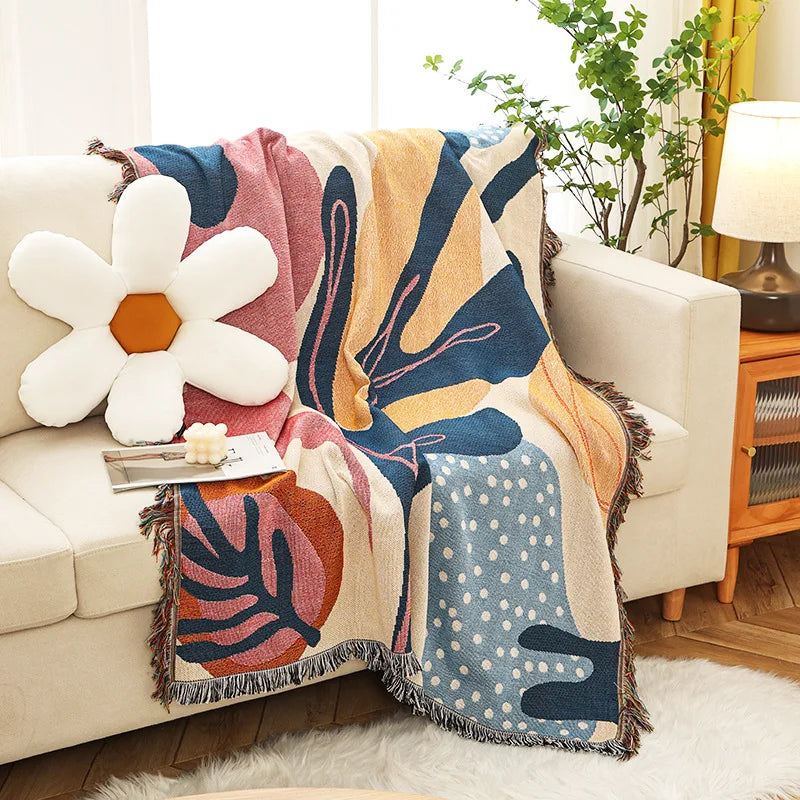 Colorful abstract patterned throw blanket draped over a sofa in a living room.