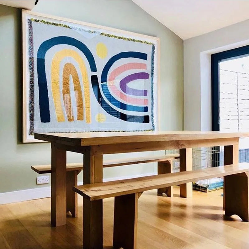 Wooden dining table with benches and abstract wall art in a room.