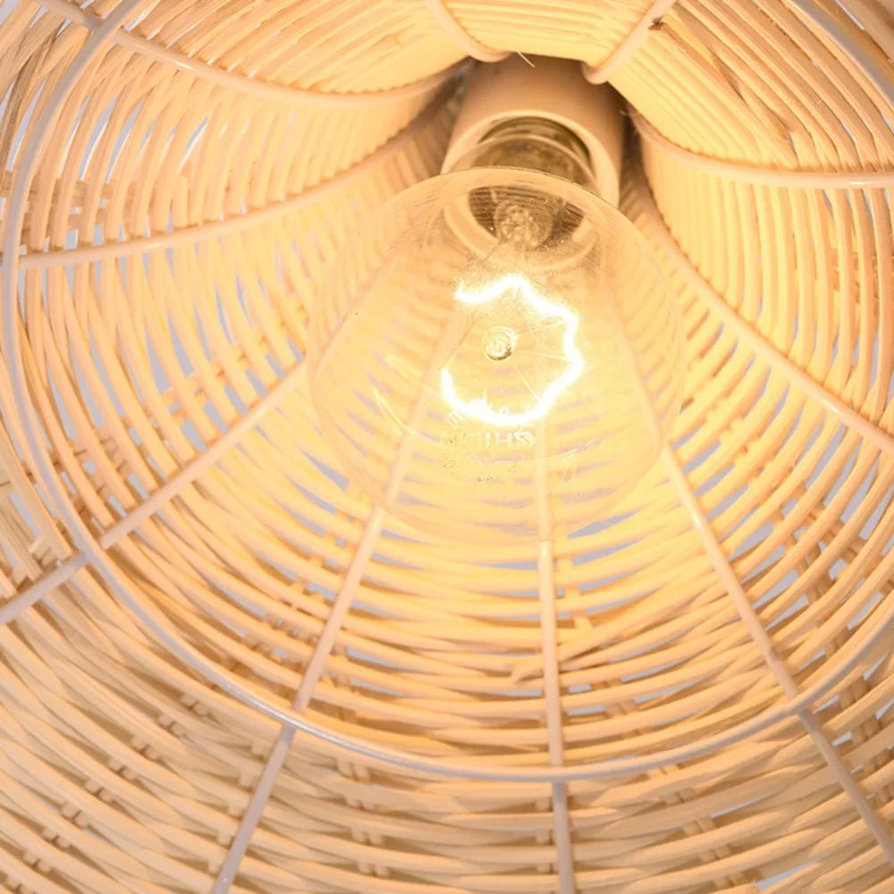 Close-up of a light bulb inside a woven rattan lampshade.