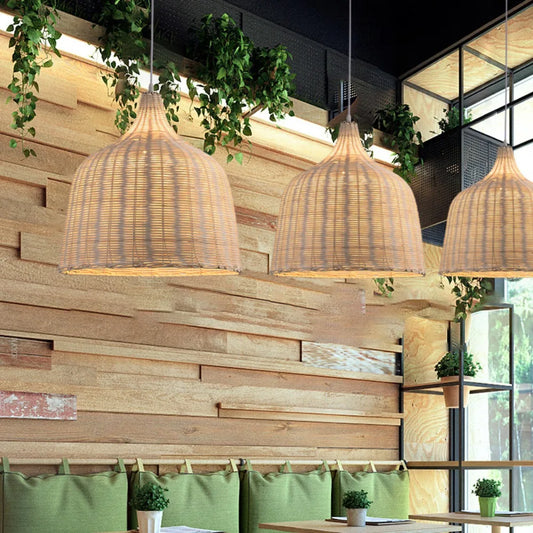 Woven pendant lights hanging above a wooden wall with greenery