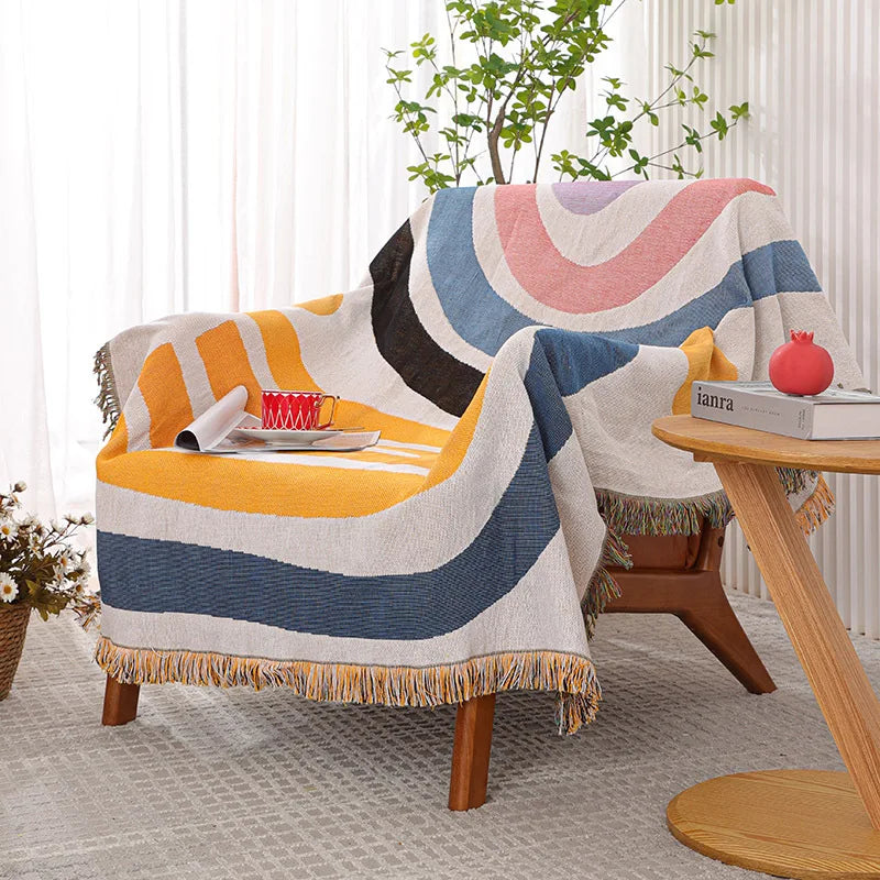 Colorful striped blanket draped over a chair in a living room setting with a small table and plant.