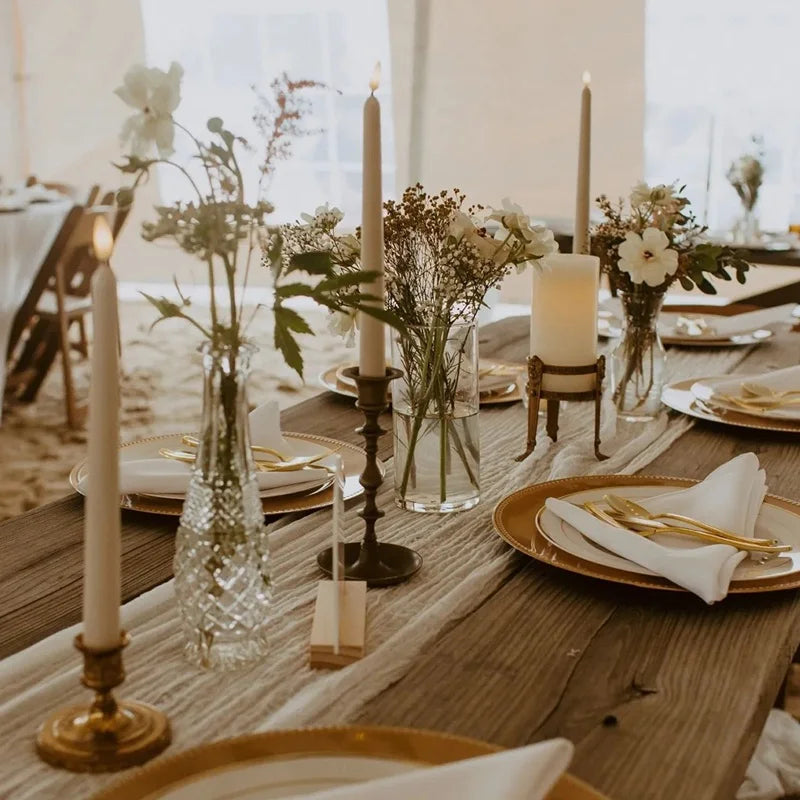Elegant table setting with candles, flowers, and cutlery on a wooden table.