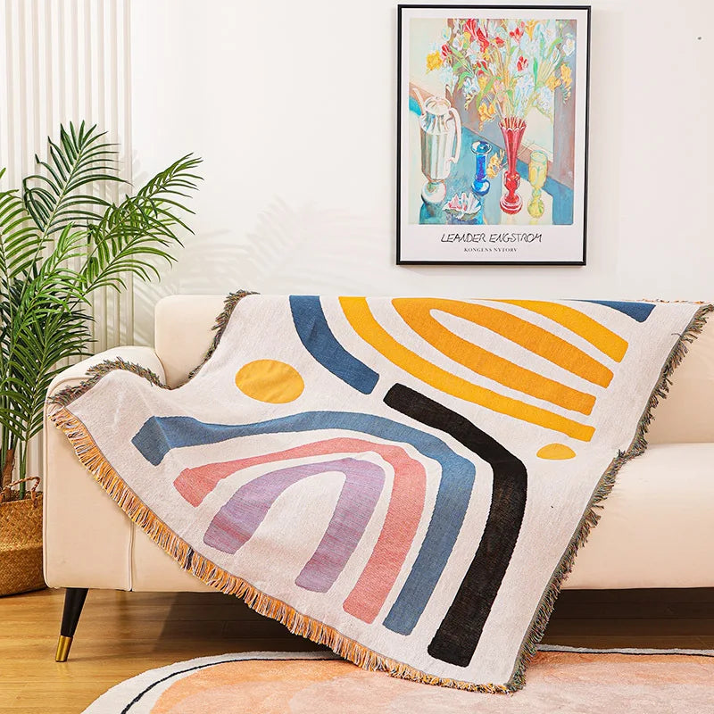 Colorful abstract-patterned throw blanket draped over a couch in a living room.