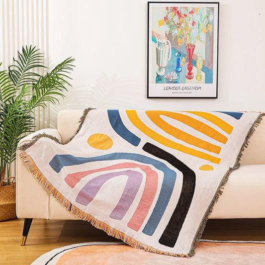 Colorful abstract-patterned throw blanket draped over a couch in a living room.