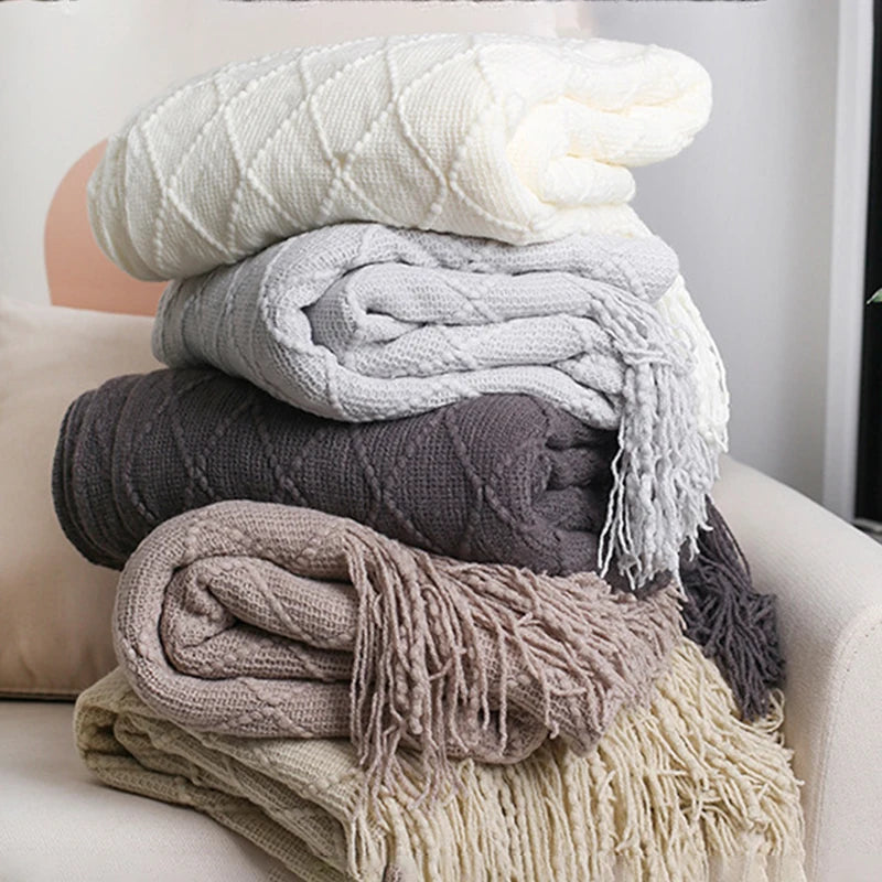 Stack of folded textured blankets in various colors on a couch.
