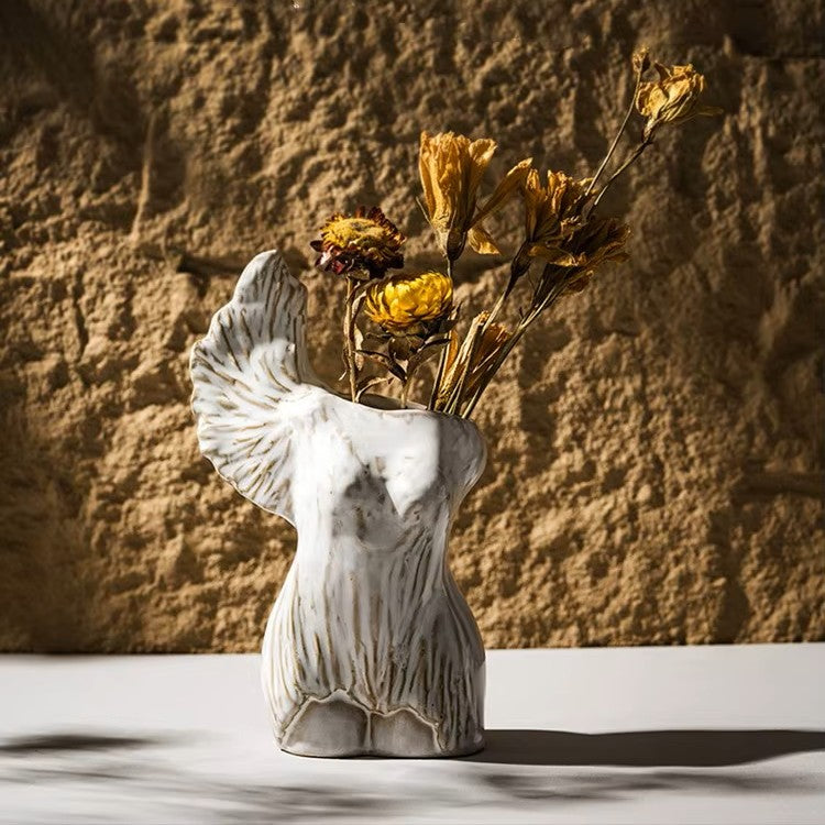 Marble-textured vase with dried flowers against a textured wall.