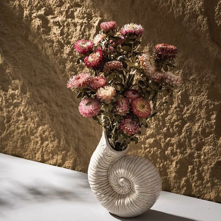 Decorative vase with pink flowers against a textured stone wall