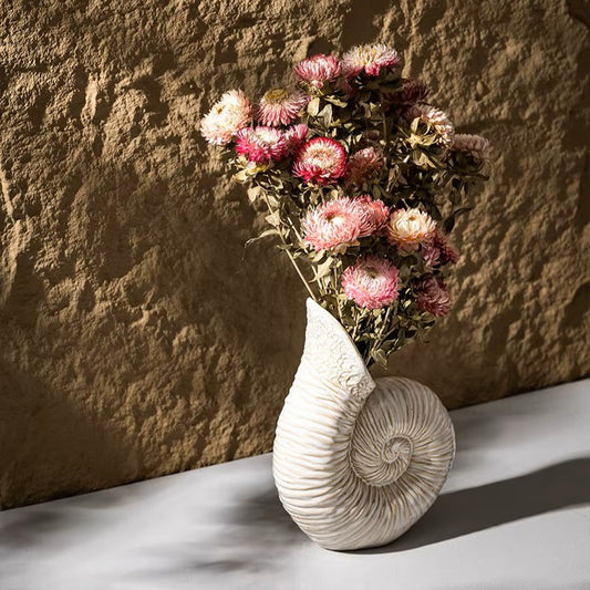 Decorative vase with pink flowers against a textured stone wall