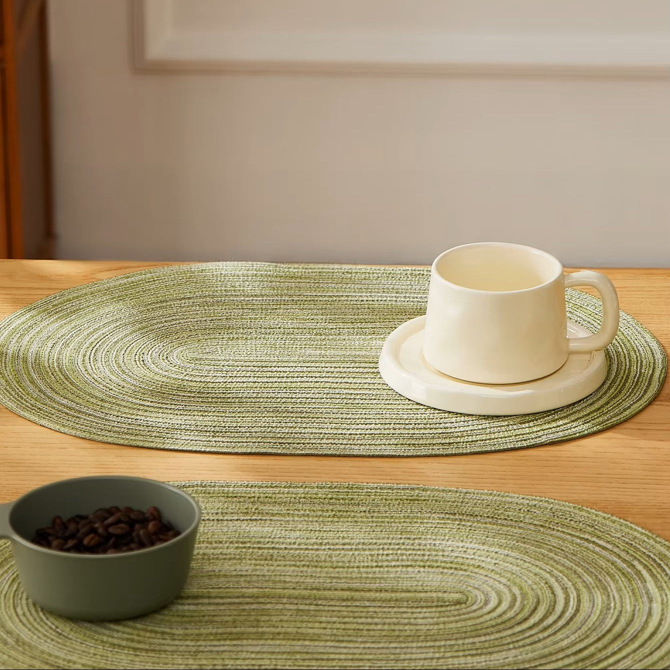 Green woven placemats with a white mug and bowl on a wooden surface.